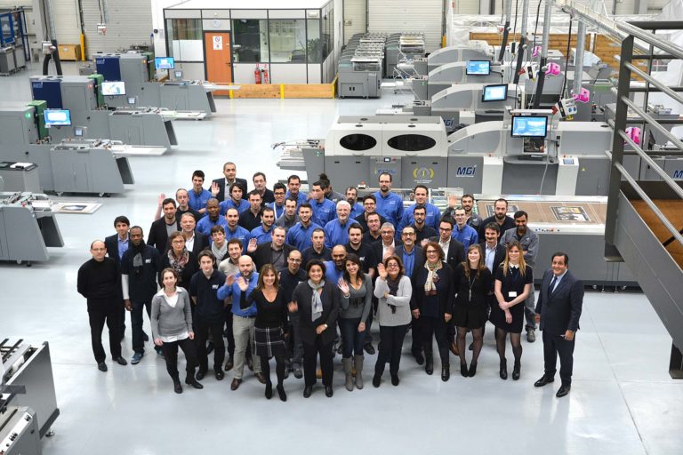 photo of the MGI Digital Technology team in its factory, surrounded by digital presses