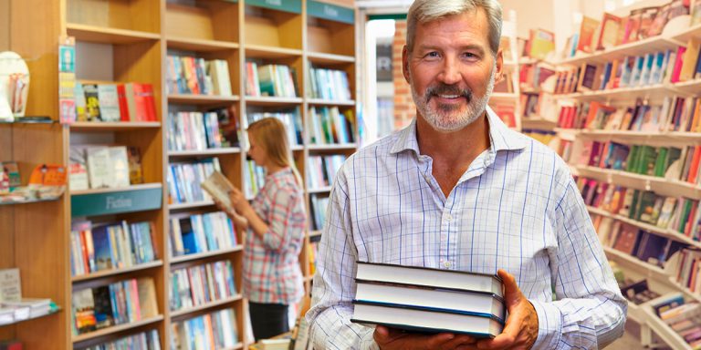 Photo of a man holding books in a bookstore