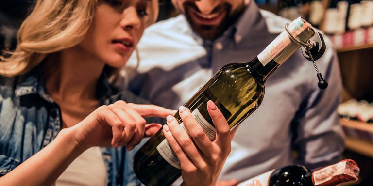 photo d'un couple regardant l'étiquette d'une bouteille de vin chez un caviste