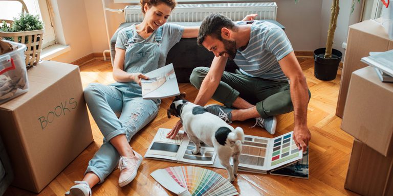 Photo of a cut with their dog looking at commercial prints in their new apartment filled with moving boxes