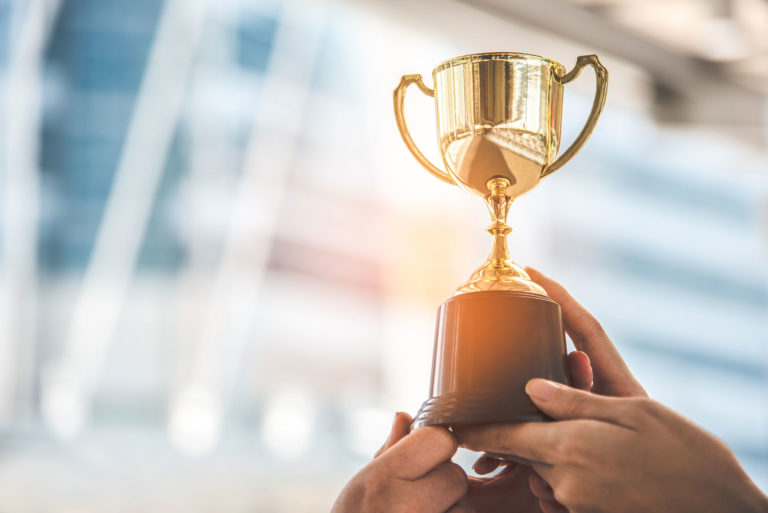 photo of hands holding a golden trophy on a light blurred background