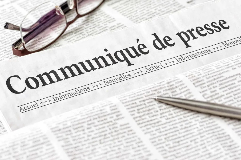 Photo of a newspaper with the title press release, with a pencil and a pair of glasses